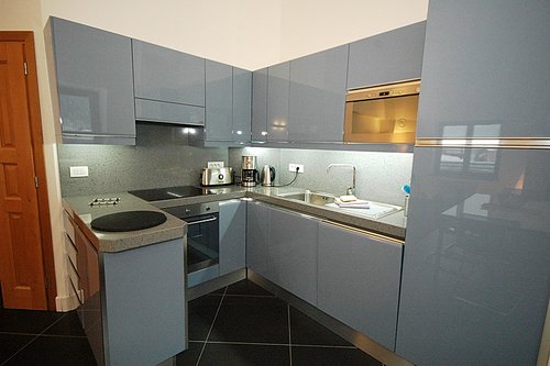 Fully fitted modern kitchen with large fridge, oven, hob, microwave and dishwasher