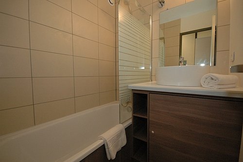 Bathroom with shower above and washing machine under basin